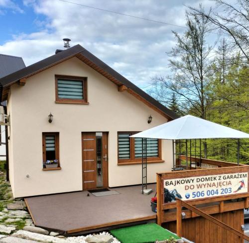 een klein huis met een patio en een parasol bij Bajkowy Domek in Szczyrk