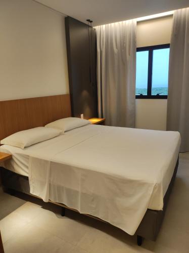 a bedroom with a large white bed with a window at Salinas Premium Resort in Salinópolis