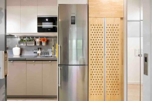 una nevera de acero inoxidable en una cocina con armarios blancos en II-II Hub Luxury New Apartments en Barcelona