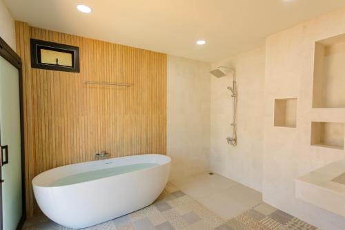 Habitación con baño con bañera blanca. en Neenlawat Riverside, en Suratthani