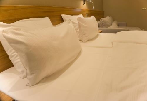 Una cama blanca con almohadas blancas. en Baltic Plaza Hotel Medi Spa, en Kołobrzeg