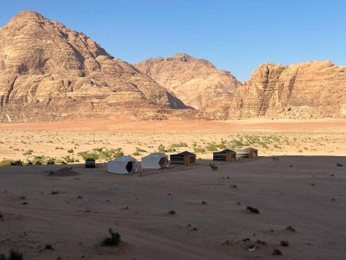 a group of huts in the desert with mountains at Experience sleep under the star in Wadi Rum