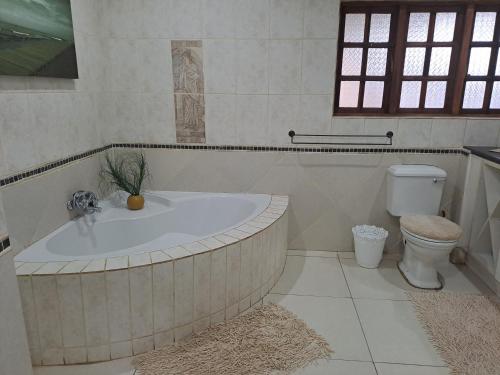 a bathroom with a bath tub and a toilet at Shangrila-innibos Country Lodge in Hartbeespoort
