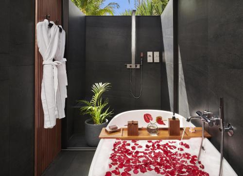 a bathroom with a bath tub covered in red petals at Palm Hotel & Spa in Petite Île