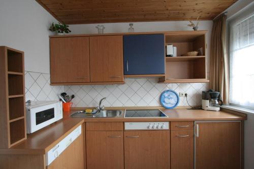cocina con armarios de madera, fregadero y microondas en Glaeßer Appartements, en Burg auf Fehmarn