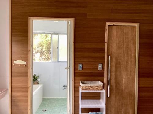 a bathroom with a wooden door and a sink and a tub at 海之恋 in Arazato