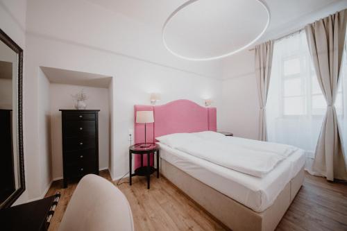 a bedroom with a large white bed and a pink headboard at Penzion Austis in Znojmo