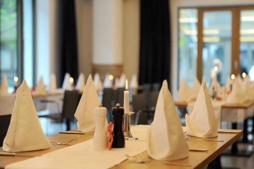 a table with white napkins and candles on it at Bayer 89 Vi Vadi Hotel in Munich