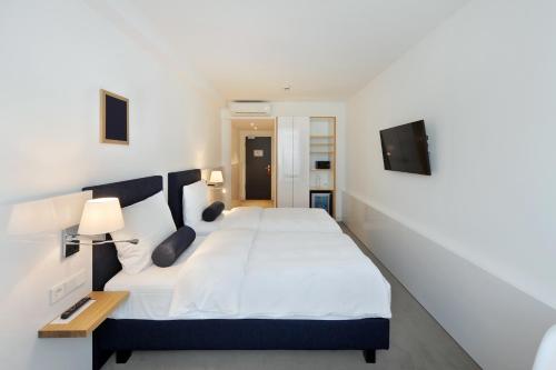 a bedroom with a large white bed and a television at Bayer 89 Vi Vadi Hotel in Munich
