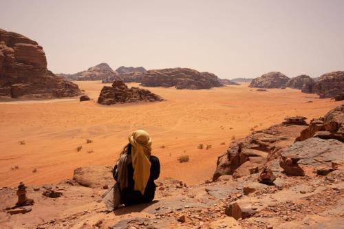 una mujer sentada en una roca en el desierto en Experience sleep under the star en Wadi Rum