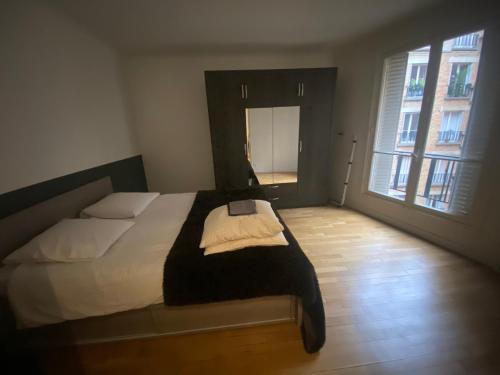 une chambre avec un lit et une grande fenêtre dans l'établissement Petit coin de paradis Paris 16, à Paris