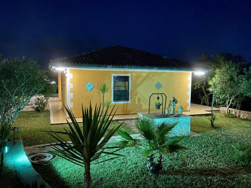 a small yellow house with a garden at night at Villa Leonardo in Canicattini Bagni
