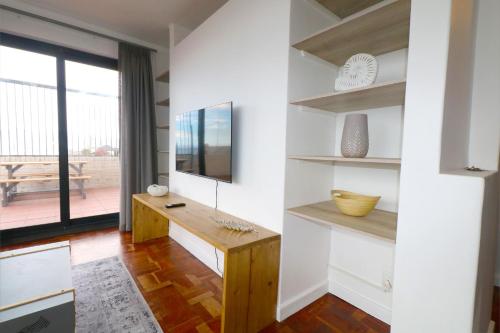 a living room with white walls and a wooden desk at South Surf Apartment in Muizenberg