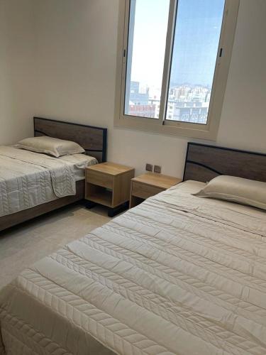 two beds in a room with two windows at أفخم شقة فندقيه بالقرب من الحرم المكي in Makkah