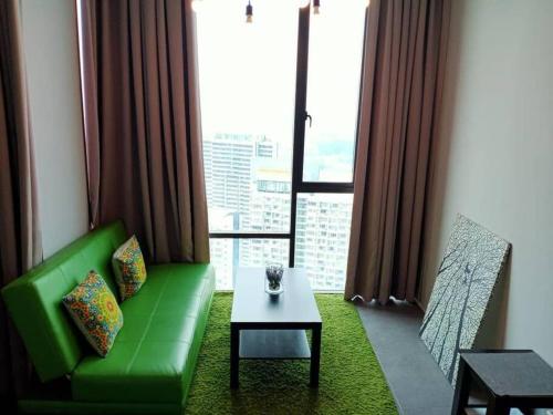 ein Wohnzimmer mit einem grünen Sofa und einem Tisch in der Unterkunft Eternally Studio Empire Damansara/Wi fi/Netflix in Petaling Jaya