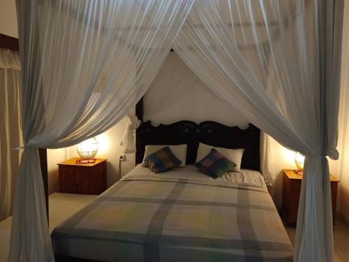 a bedroom with a canopy bed with white curtains at Lumbung Sari Home Stay in Amed