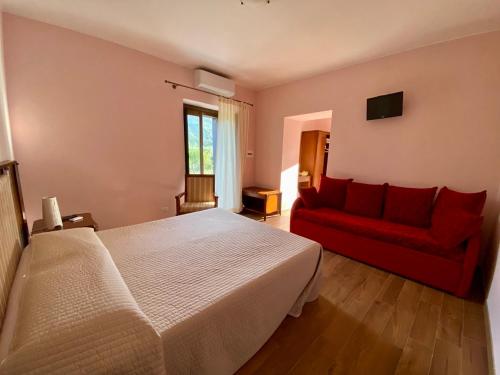 a bedroom with a bed and a red couch at La Porta delle Gole in Motta Camastra