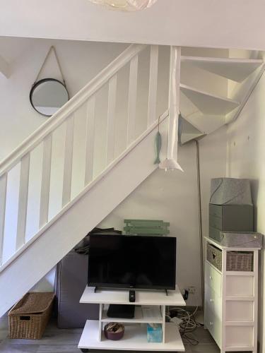 - un salon avec une télévision sous un escalier dans l'établissement Cottage Charmant 2 personnes proche de la mer, à Blonville-sur-Mer