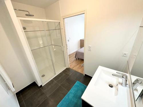 bagno con doccia e lavandino bianco di Grand appartement neuf de standing – Top Cosy a Larmor-Plage