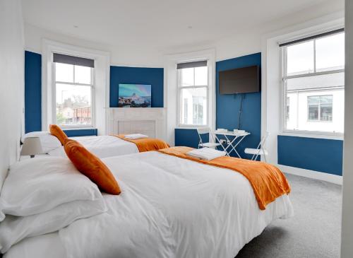 2 camas en una habitación con paredes y ventanas azules en Homesly Guest Rooms, Comfortable En-suite Guest Rooms with Free Parking and Self Check-in, en Berwick-Upon-Tweed