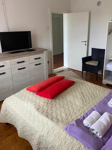 a bedroom with a large bed with red pillows on it at Mala Oaza in Čačak