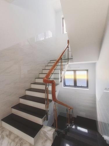 a staircase in a house with white walls and wooden railings at KHÁCH SẠN VĂN KHANG in Bạc Liêu