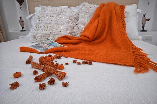 an orange blanket on a bed with a book and spices at Affittacamere Capri Dolce Vita in Capri