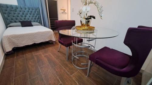 Habitación con mesa, sillas moradas y cama en Relax moderna tiny suite, en Manta
