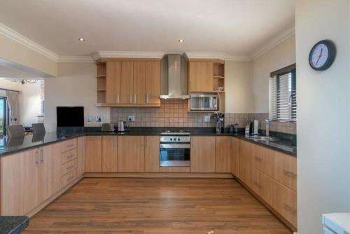 a kitchen with wooden cabinets and a clock on the wall at SW2 - Pezula Luxury Villa in Knysna