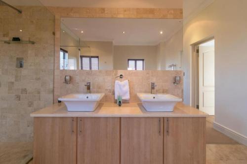 a bathroom with two sinks and a large mirror at SW2 - Pezula Luxury Villa in Knysna