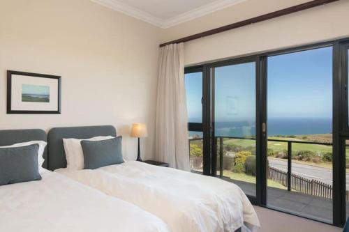 two beds in a bedroom with a view of the ocean at Pezula Luxury Villa SW2 in Knysna