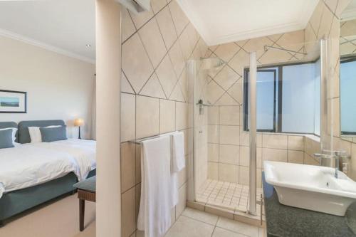 a bathroom with a bed and a tub and a sink at Pezula Luxury Villa SW2 in Knysna