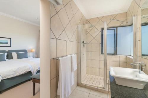 a bathroom with a bed and a tub and a sink at SW2 - Pezula Luxury Villa in Knysna