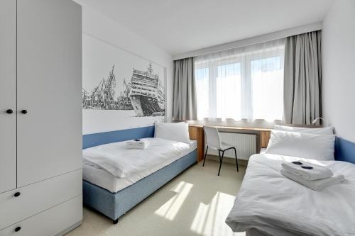 a hotel room with two beds and a desk at Apartgdynia in Gdynia