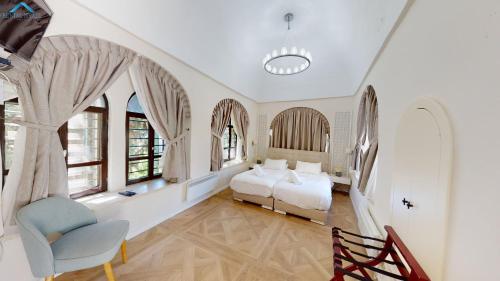 a bedroom with two beds and a chair and windows at VILLA MAMILLA - Boutique suites in Jerusalem