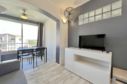 un salon avec une télévision et une table avec des chaises dans l'établissement Bright 26 m with pool in Frejus, à Fréjus