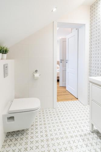 a bathroom with a white toilet and a white tile floor at Apartamenty Defala i Strefa Relaksu Natural Touch in Rymanów-Zdrój