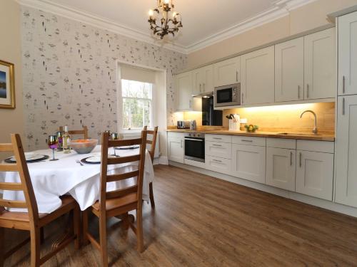 a kitchen with white cabinets and a table with chairs at Redwood Rise Apartment Keswick in Keswick