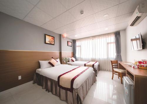 a hotel room with two beds and a desk at Arise Seaside Hotel in Nha Trang