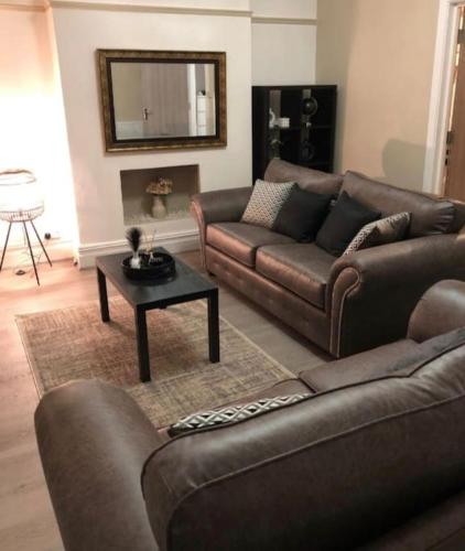 a living room with two brown couches and a table at Three Bedroom Apartment with Roof Terrace Near City Centre in Cardiff