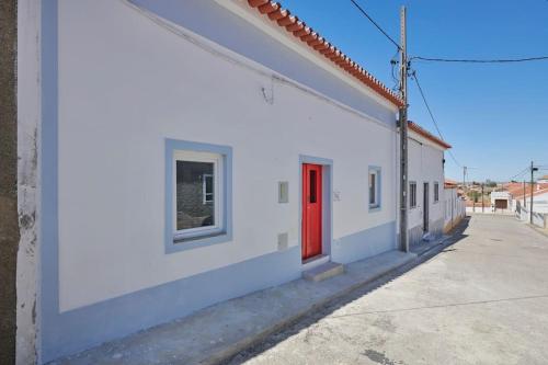 un bâtiment blanc avec une porte rouge dans une rue dans l'établissement Rustic & Aesthetic House in Alqueva with Pool, à Granja