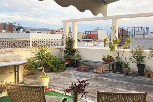 einen Balkon mit einem Tisch, Stühlen und Pflanzen in der Unterkunft Sacred Way rooftop apartment in Athen