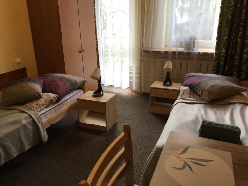 ein Hotelzimmer mit 2 Betten, einem Tisch und einem sidx sidx in der Unterkunft Willa Ewa in Busko-Zdrój