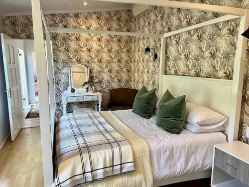 a bedroom with a canopy bed with green pillows at Stirling Cottage in Durban