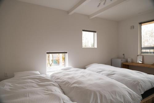 two white beds in a room with two windows at HOTEL BOTH in Shari
