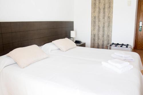 a white bed with two white pillows on it at Grupoandria Hotel Platja Gran in Ciutadella