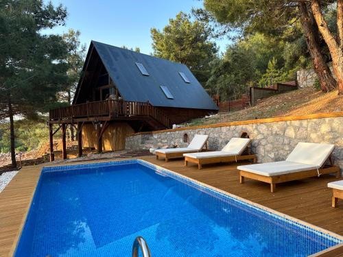 a swimming pool with chairs and a house at Panurlawoodenhouse özel havuz& sauna mavi in Urla