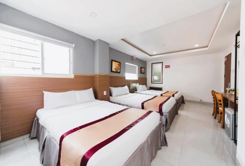 a hotel room with three beds and a television at Arise Seaside Hotel in Nha Trang