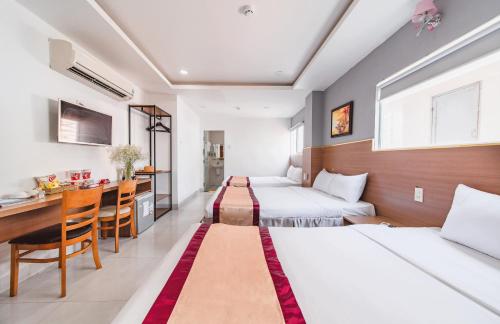 a hotel room with two beds and a desk at Arise Seaside Hotel in Nha Trang