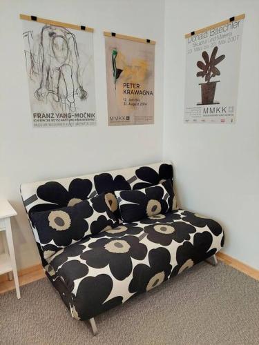 a black and white couch in a room with posters at Gemütliche Stadtwohnung in Klagenfurt in Klagenfurt